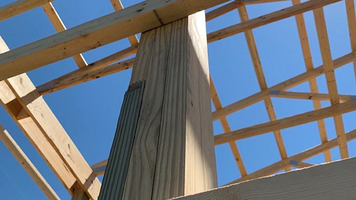 Laminated structural column standing in a post frame building under construction